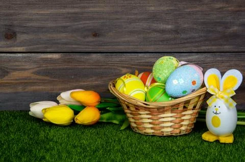 Easter. A wicker basket filled with easter eggs and colorful tulips bouquet o Stock Photos