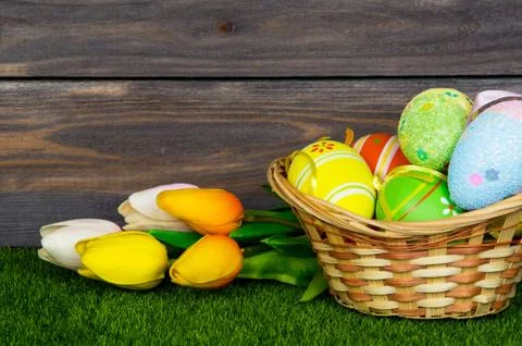 Easter. A wicker basket filled with easter eggs and colorful tulips bouquet o Stock Photos