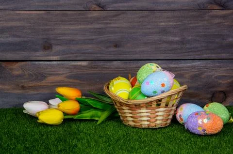 Easter. A wicker basket filled with easter eggs and colorful tulips bouquet o Stock Photos