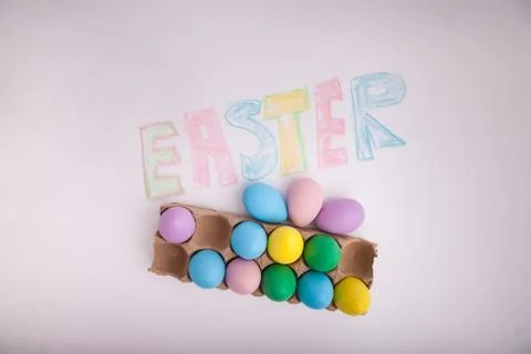 Easter written in chalk on white background with carton of Easter egges Stock Photos