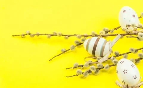 Easter yellow background with eggs hanging on branches of catkins Stock Photos