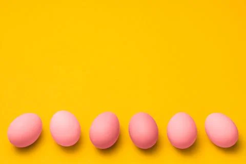 Easter yellow background with a row of pink colored eggs with copy space on top Stock-Fotos