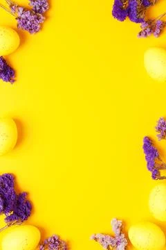 Easter yellow eggs with purple flowers on yellow background. Flat lay, copy s Stock Photos