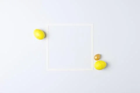 Easter yellow eggs with white frame on white background. Flat lay, copy space Stock Photos