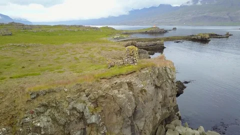 Eastern Icelandic drone shot of small rock pile and lighthouse near coast Stock Footage 84442148