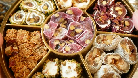 Eastern sweets with nuts, candy, metal vase, dates on wooden background, clos Video stock 129384769