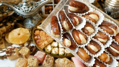 Eastern sweets with nuts, candy, metal vase, tea, dates on wooden background, Stock-Footage 138639897
