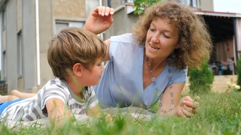 Easy parenting concept. Happy mother and child lying on the grass. Video stock 95608053