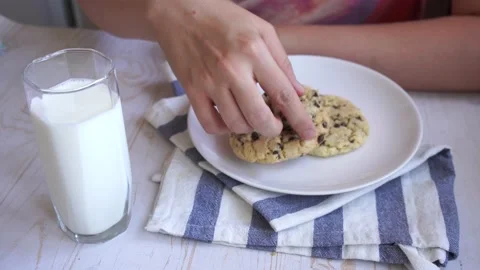 Eat fresh baked classic chocolate chip cookies with nuts on a plate, glass milk Stock Footage 134997341