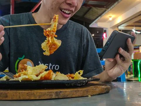 Eat while playing mobile Stock Photos