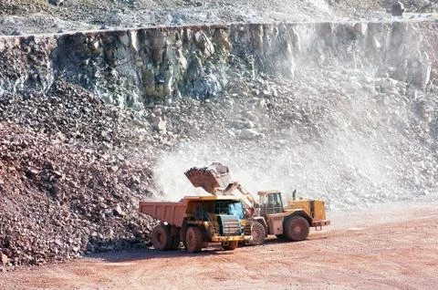 Eath mover loading stones on a dumper truck Stock Photos