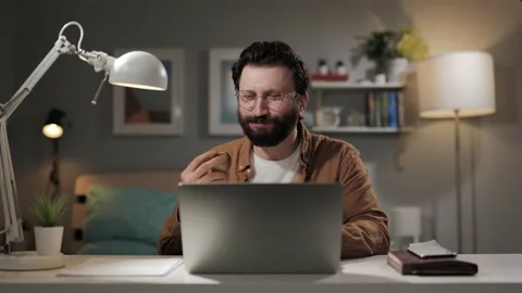 Eating apple. Happy man at computer eats apple. Smiling freelancer on proper Видео 196201792
