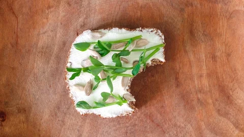 Eating bite by bite small toast with cream cheese, pea sprouts and sunflower Stock Footage 129173951