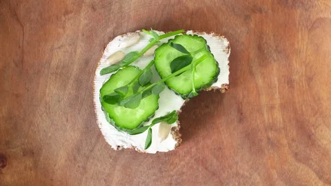 Eating bite by bite small toast with cream cheese, cucumber, pea sprouts Stock Footage 129174040