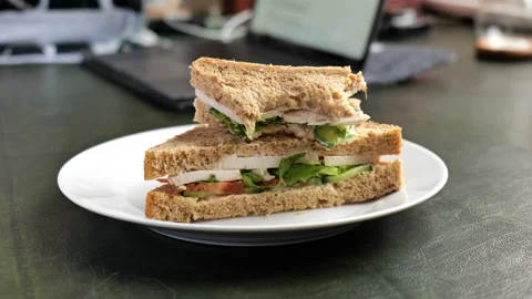 Eating a chicken salad sandwich while working at a laptop Stock Footage 147498676