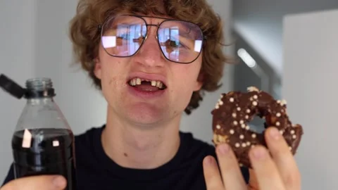 Eating chocolate donut and drinking soda with satisfied look and messy mouth in  Stock Footage 312202272