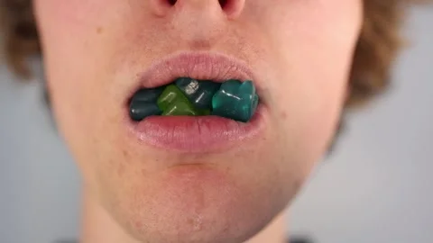 Eating colorful gummy bears with missing front teeth in an extreme closeup illus Stock Footage 312203021