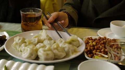 Eating Dumplings With Chopsticks at a Table With Tea and Side Dishes in Beijing Stock Footage 345745218