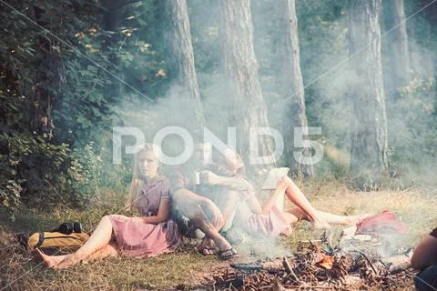 Eating food, reading book and entertainment. Friends relax at bonfire flame with Stock Photos