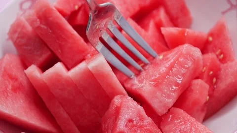 Eating fresh watermelon slices with a fork on a plate Stock Footage 345474157