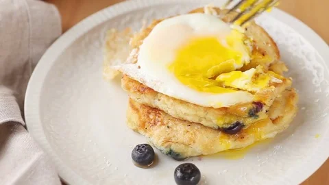 Eating fried egg over blueberry pancakes Stock Footage 74903326