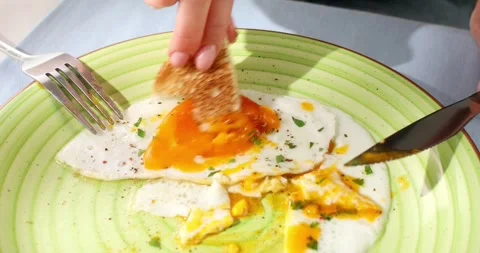 Eating fried eggs with a bread on a green plate. close-up. angle view. Stock Footage 246323337