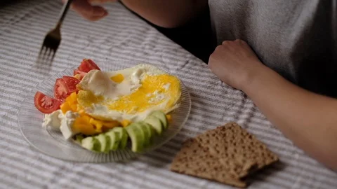 Eating fried eggs for breakfast with fresh vegetables and cheese. Stock Footage 105359336