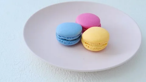 Eating macarons of different colors on a pink plate Stock Footage 254079722
