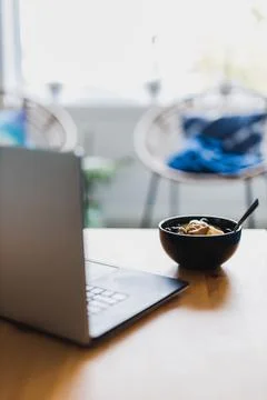 Eating mango blueberries oatmeal while working from home on a laptop, remote  Stock Photos
