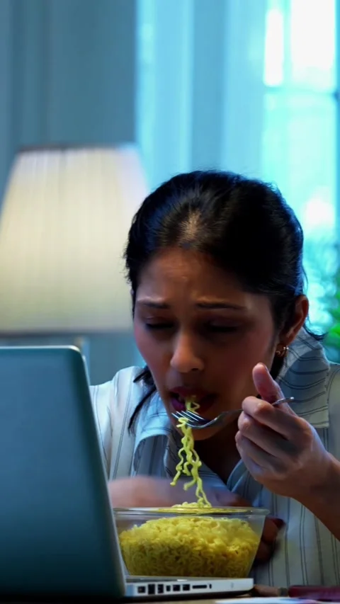 Eating noodles while working, Indian businesswoman joins video call at office Stock Footage 342572833