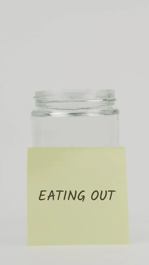Eating out text or word on yellow sticky note attached to glass jar Stock Footage 311723572