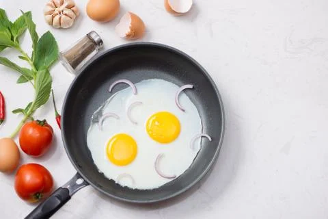 Eating in the process, fried eggs in a frying pan for breakfast on a white ba Foto stock