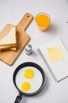 Eating in the process, fried eggs in a frying pan, toast  and orange juice fo Foto stock