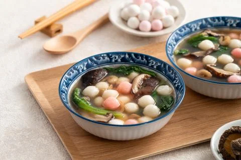 Eating red and white small tangyuan with savory soup and vegetable. Stock Photos