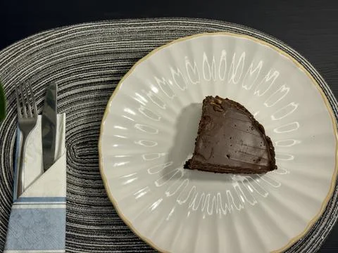 Eating slice of chocolate cake with fork from white plate, top view flat lay Stock-Fotos