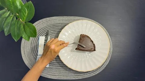 Eating slice of chocolate cake with fork from white plate, top view flat lay Stock Photos