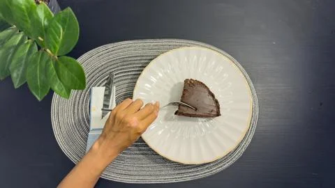 Eating slice of chocolate cake with fork from white plate, top view flat lay Stock Photos