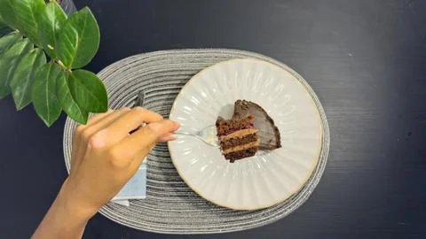 Eating slice of chocolate cake with fork from white plate, top view flat lay Stock-Fotos