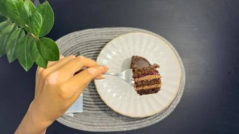 Eating slice of chocolate cake with fork from white plate, top view flat lay Stock Photos