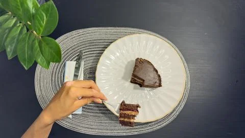 Eating slice of chocolate cake with fork from white plate, top view flat lay Stock Photos