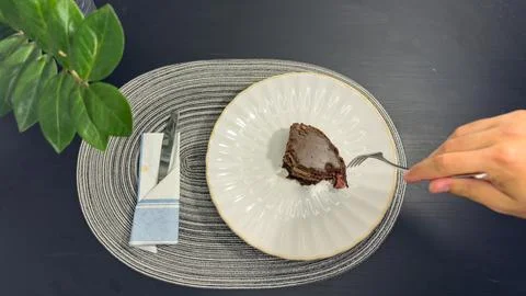 Eating slice of chocolate cake with fork from white plate, top view flat lay Stock Photos