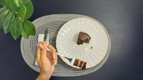 Eating slice of chocolate cake with fork from white plate, top view flat lay Stock-Fotos