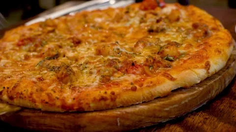 Eating Slice of pizza freshly cooked pizza from oven and places on pizza paddle Video stock 336586729