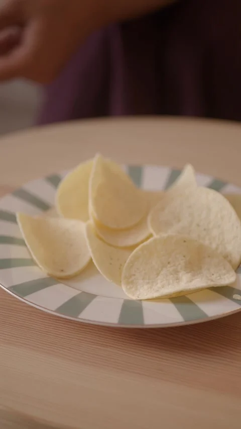 Eating snacks with potato chips on a plate in a home setting Stock Footage 346193360
