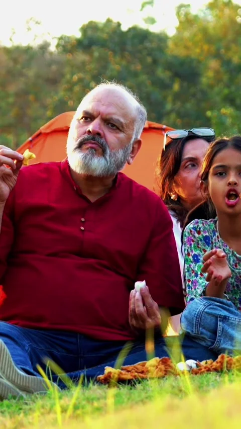 Eating snacks while camping outdoors, Indian family smiles enjoys warm bonding Stock Footage 342839091