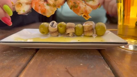 Eating Spanish Tapas and Drinking a Beer Sitting Outdoor on a Wooden Table in a Stock Footage 334836726