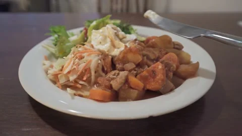 Eating stew with salad at table Stock Footage 323506053