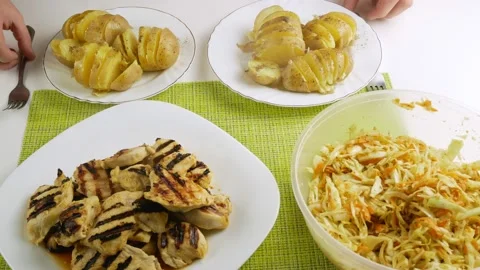 Eating at the table.With a fork take the chicken and potatoes.The cabbage salad. Video stock 131605484