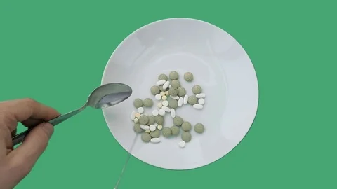Eating the tablets from a dish on green screen - medicine concept Video stock 70701420