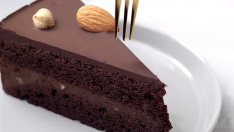 Eats with fork a piece of chocolate cake on a black plate. Stock Footage 130618629